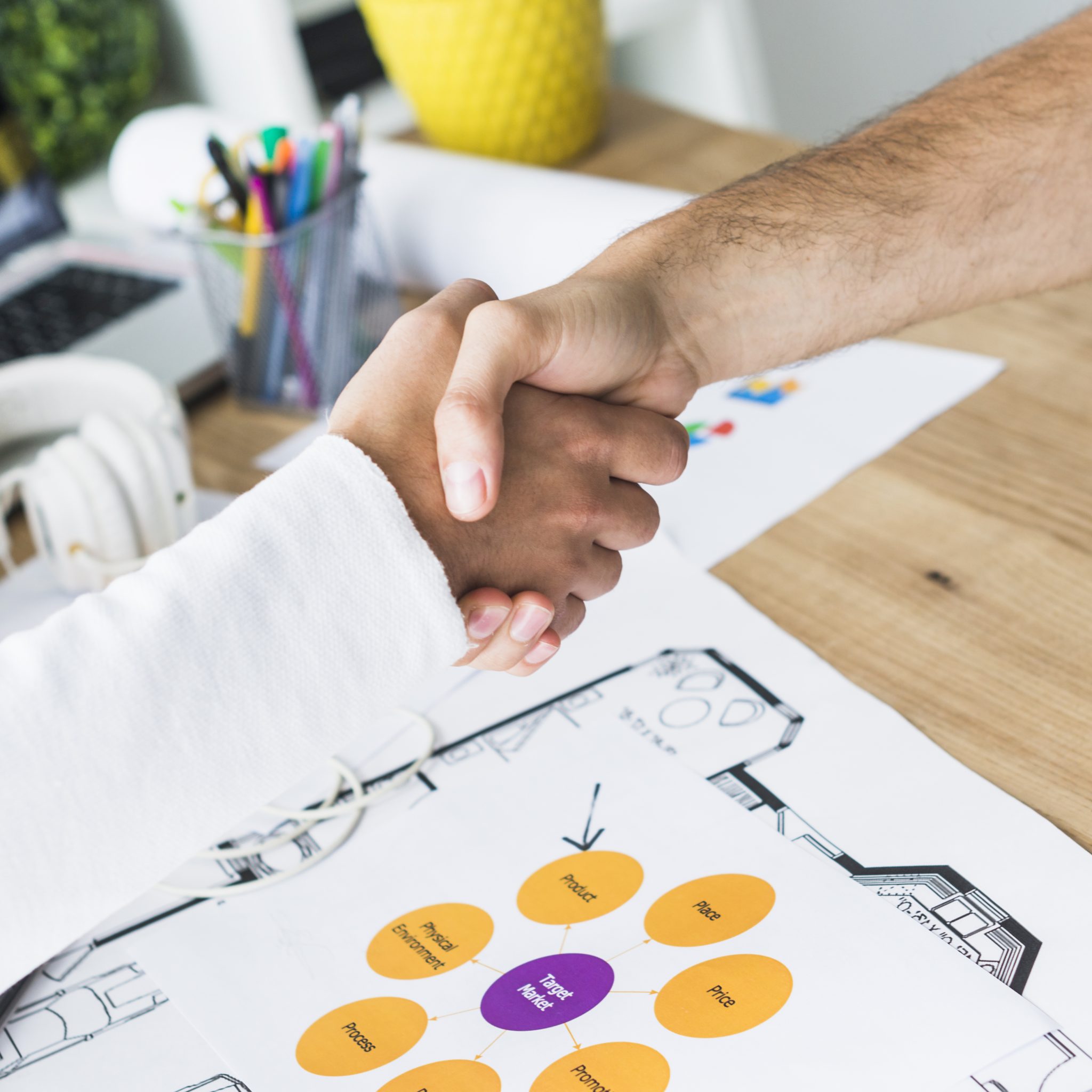 close up two businessmen shaking hands desk scaled